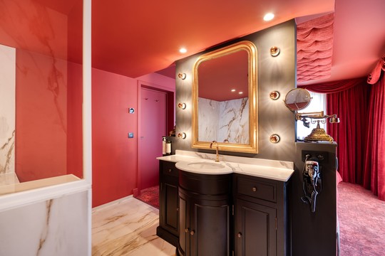 Salle de bain raffinée de la Suite Cabaret Rouge à Liège, offrant une douche à l’italienne moderne et un jacuzzi pour un confort et une détente optimale durant votre séjour.