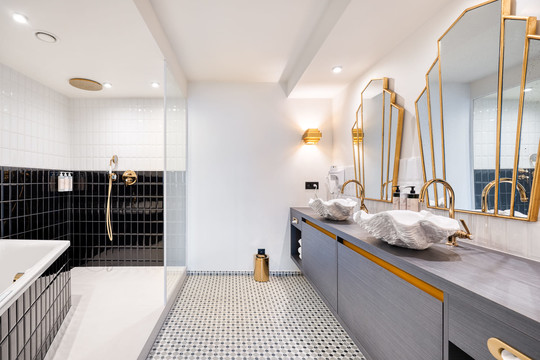 Salle de bain élégante de la Suite Gatsby avec bain à bulles privatif, marbre raffiné et douche à l’italienne dans notre hôtel 4 étoiles à Liège.