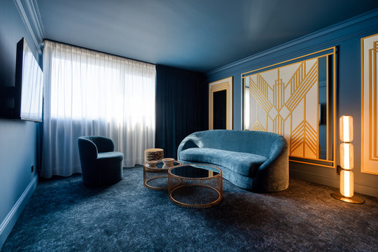 Ambiance feutrée dans le salon de la Suite Gatsby à Liège : un espace élégant aux tons chauds, parfait pour se détendre après un moment de bien-être dans le jacuzzi.